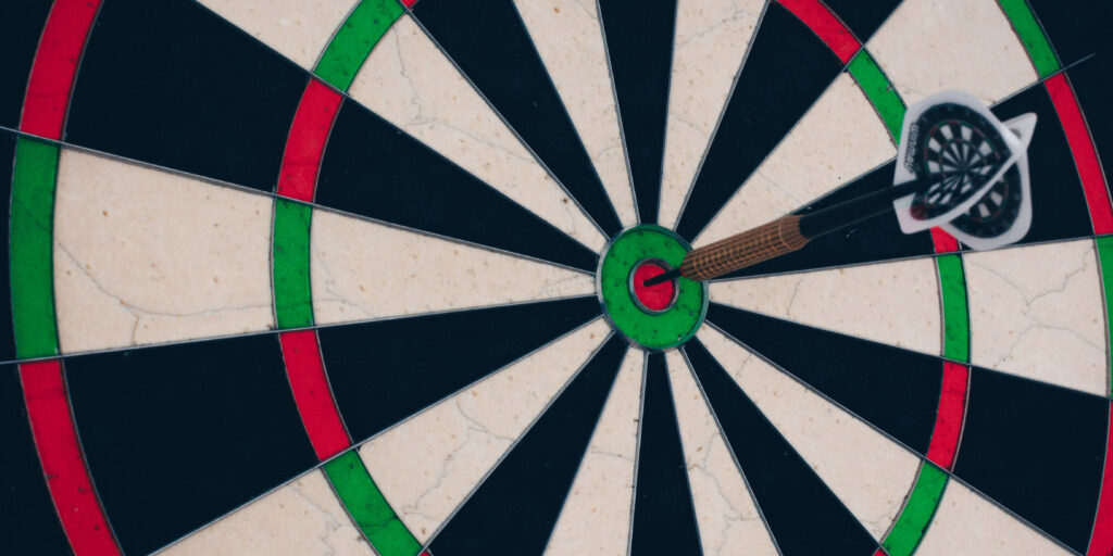 A single dart on bullseye on a black, white, green and red dartboard.