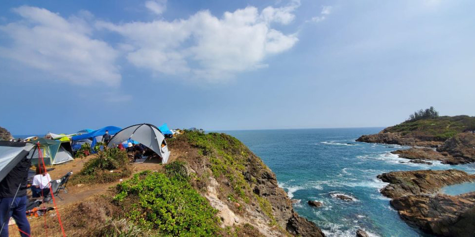 Campers on a cliff at Tung Lung Chau campsite overlooking the ocean below.