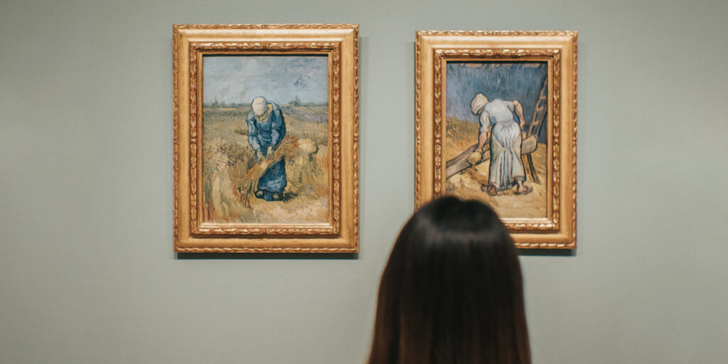 Woman standing in front of two hanging paintings.
