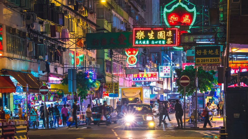 Hong Kong street lit up by neon signs at night.