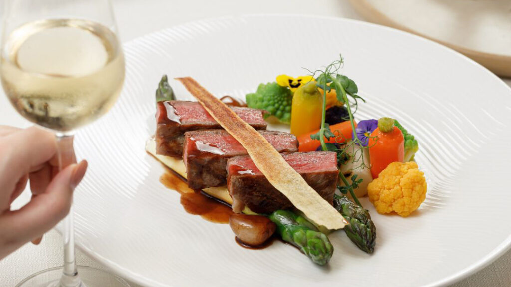 A beautifully plated meat dish with edible flowers.