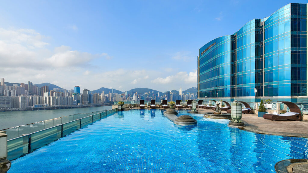 Big outdoor hotel pool overlooking Hong Kong during the day.