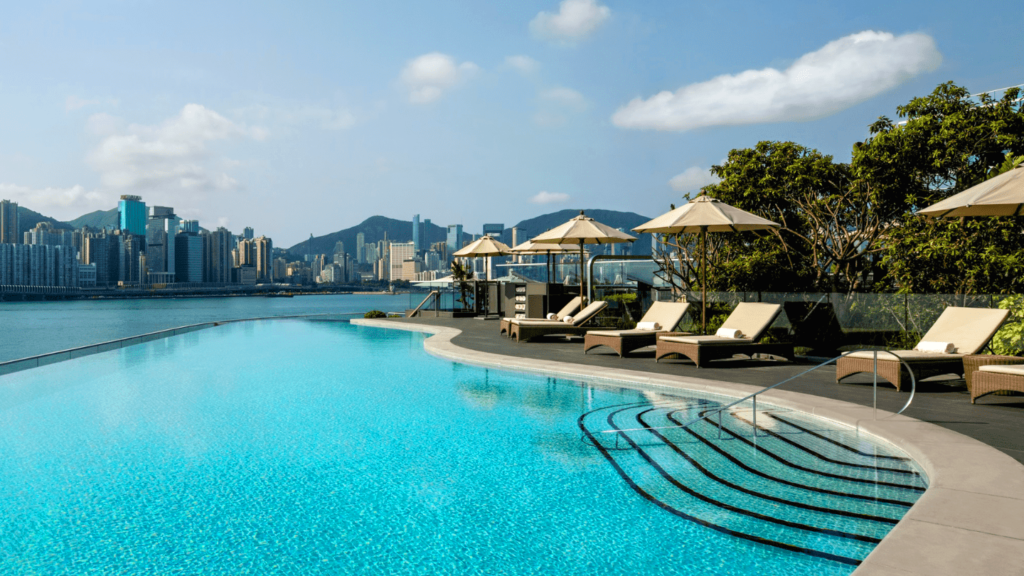 Loungers with umbrellas alongside a pool overlooking the Hong Kong harbour