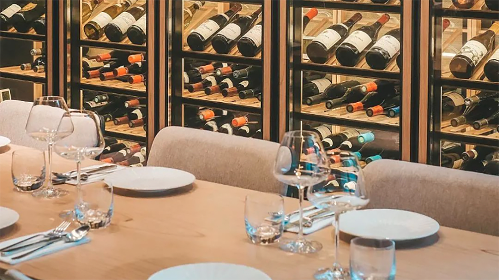 AROMA WINE BISTRO restaurant interior. Set dining table with wine fridges behind.