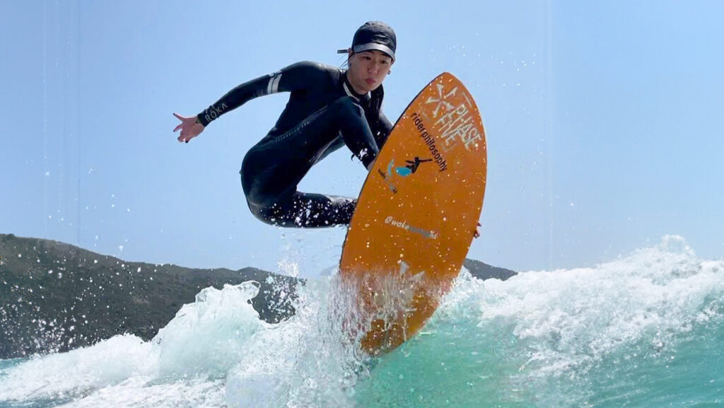 Woman surfing a wave on an orange surfboard
