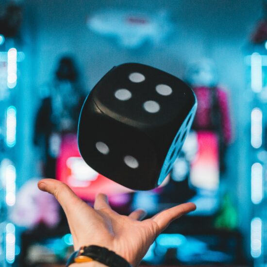 Hand throwing a large black dice into the air.